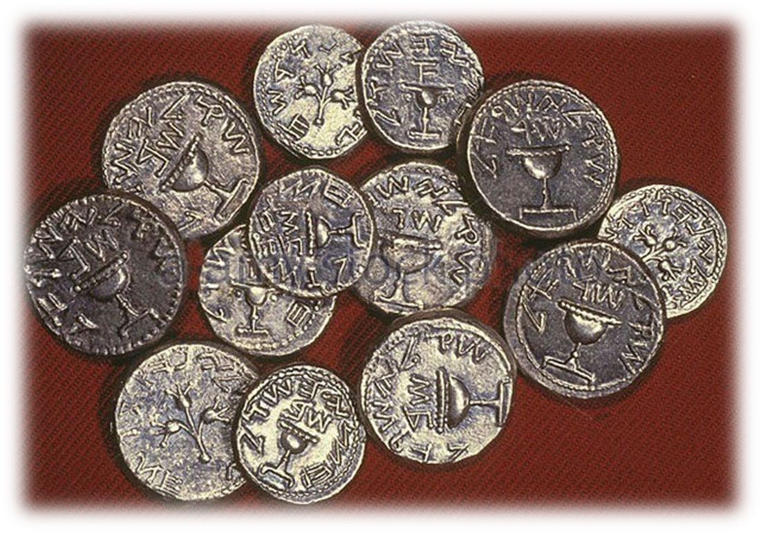 A heap of ancient silver coins stamped with cups and plants, lying on a red cloth