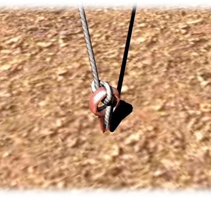 A cord tied to a metal pin driven into sandy ground