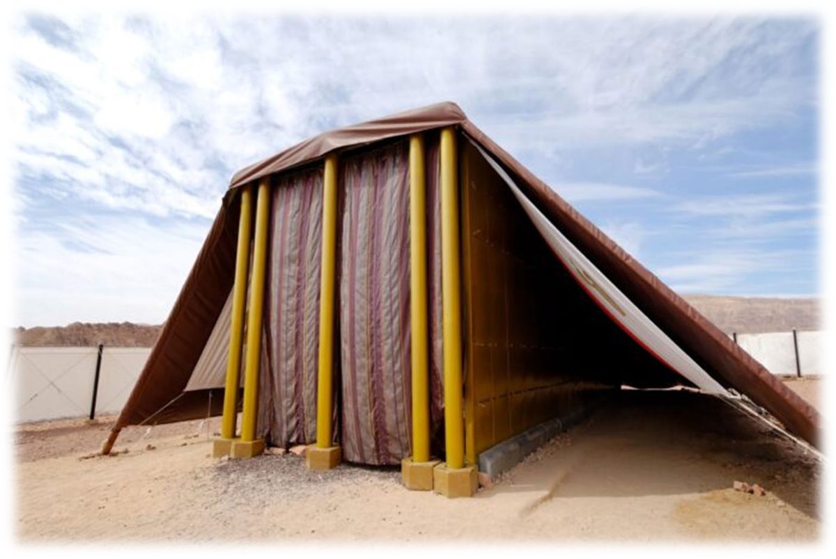 A full-size model of the Tabernacle building standing in the desert: the covering of skins drawn over the frame, and at the front the Door hanging of white linen embroidered in blue, purple and scarlet between gold-covered pillars