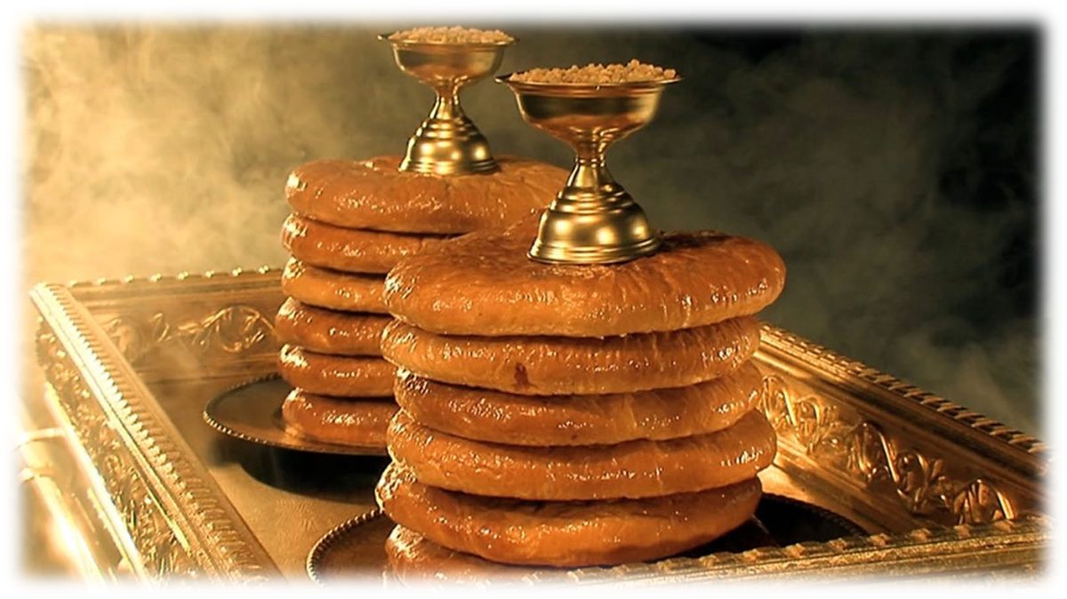 Two stacks of round loaves on a golden tray, with two small golden vessels of frankincense standing beside them