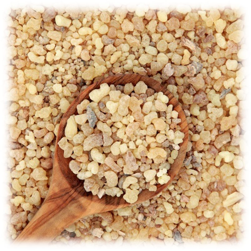 A wooden spoon heaped with pale amber granules of frankincense resin