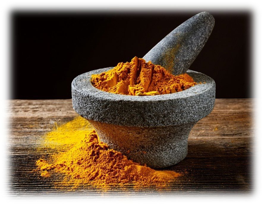 A stone mortar and pestle heaped with fine golden-orange powder, more of the powder spilled on the wooden table beneath