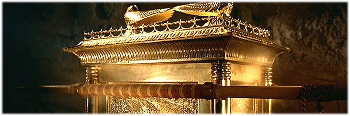 Close view of the upper part of a golden Ark, the crown of gold running round its rim beneath the cherubim, with a gilded stave passing through the rings